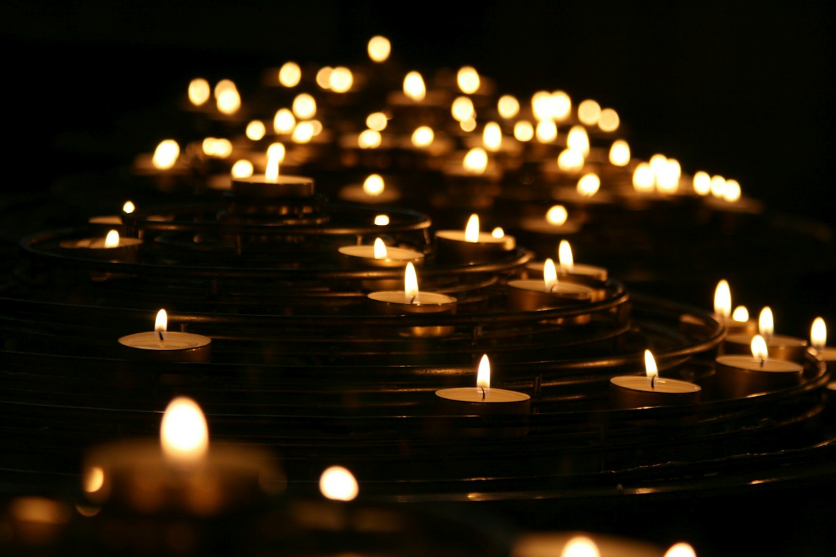 Dozens of small candle flames glowing in the dark
