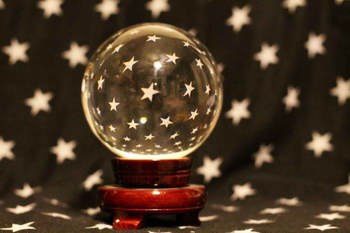 A crystal ball etched with stars on dark starry cloth
